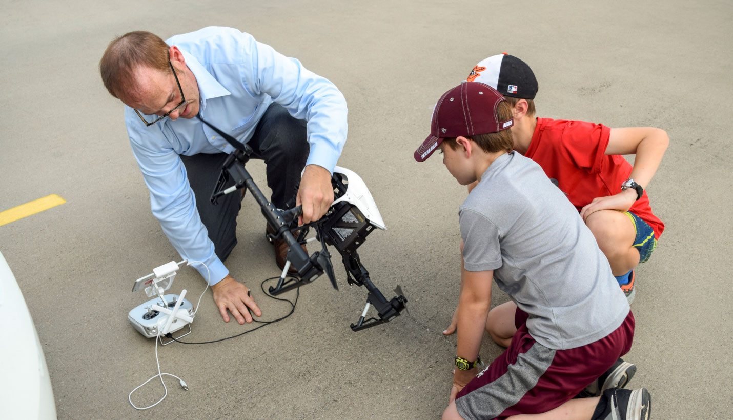 Steve Meyers showing children how to get a drone-camera off the ground, Brian Roeder (children) - 