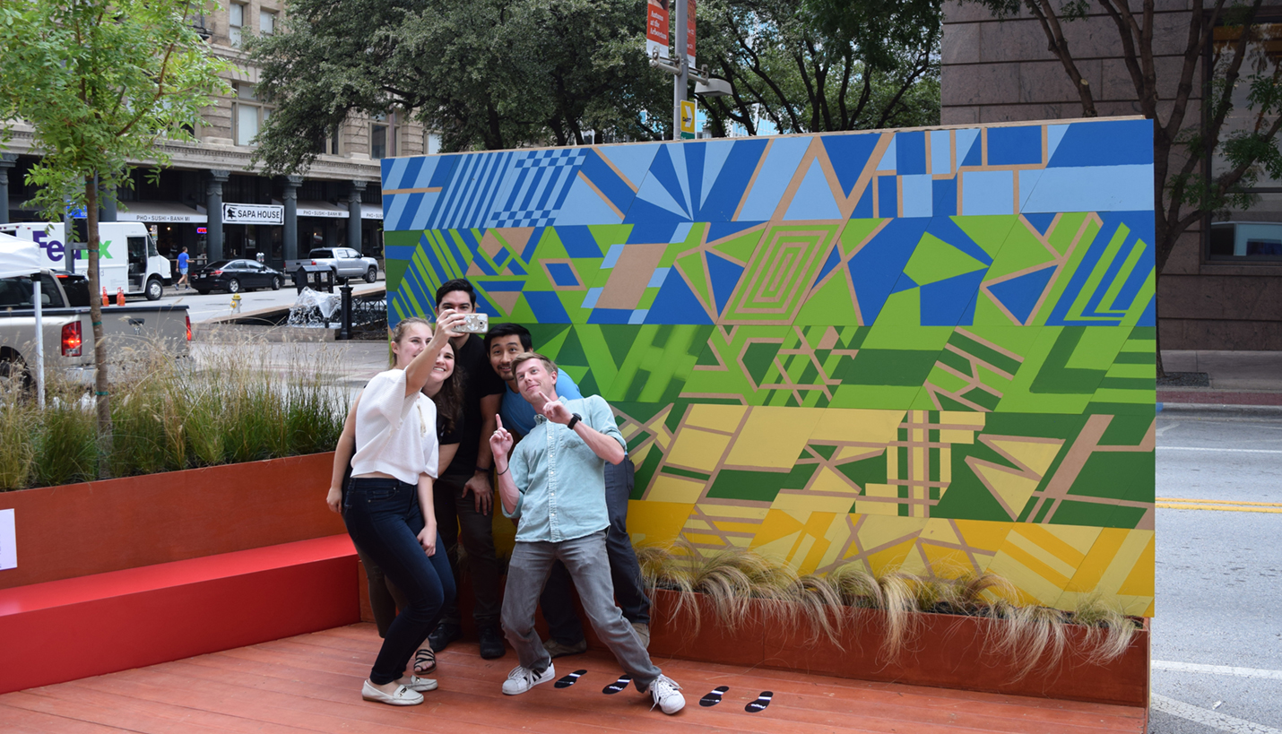 Members of the Page Dallas team demonstrate selfies in front of their Park(ing) Day mural. - Page